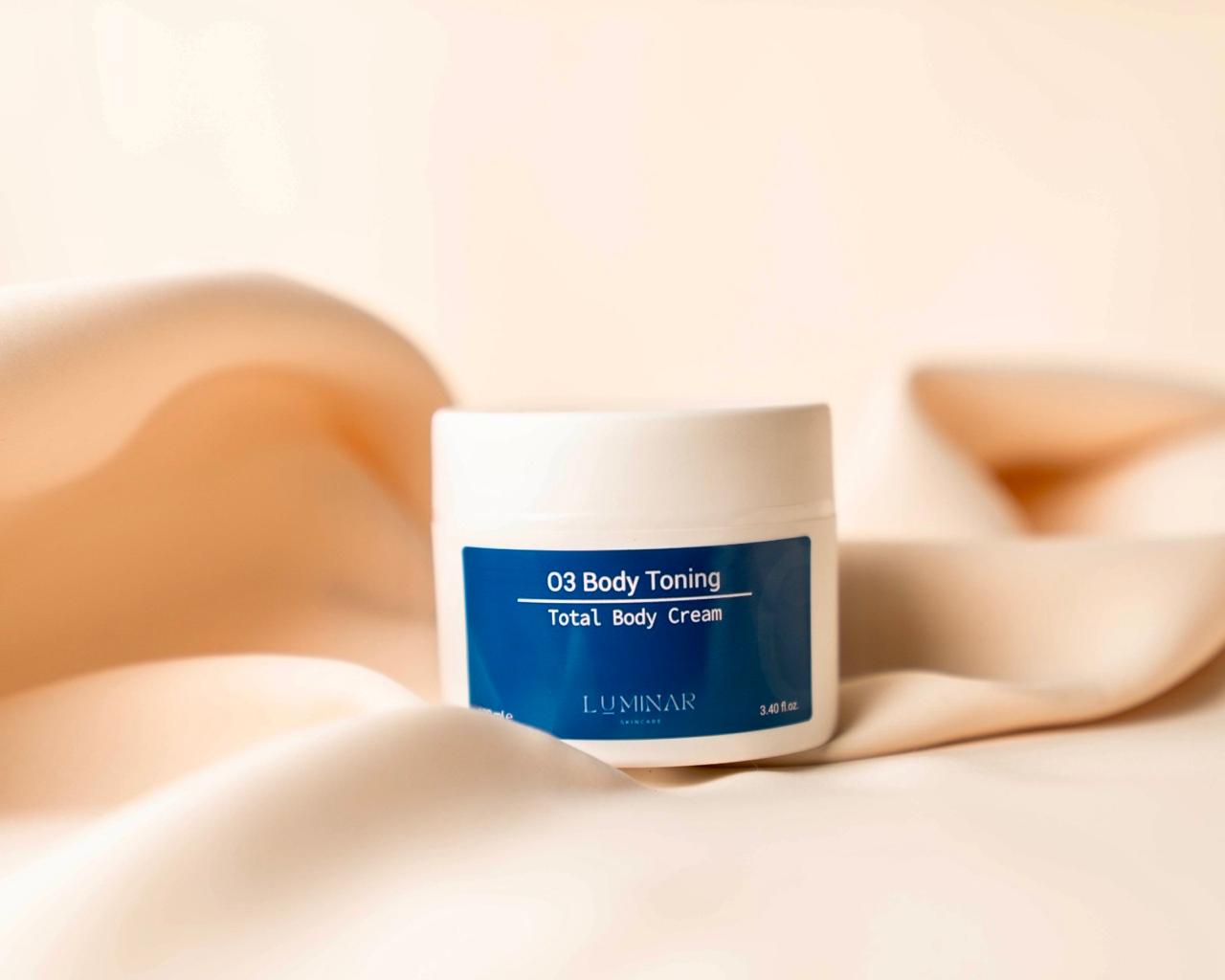 Luminar O3 Body Toning product on neutral peach fabric, conveying firming and rejuvenation.
