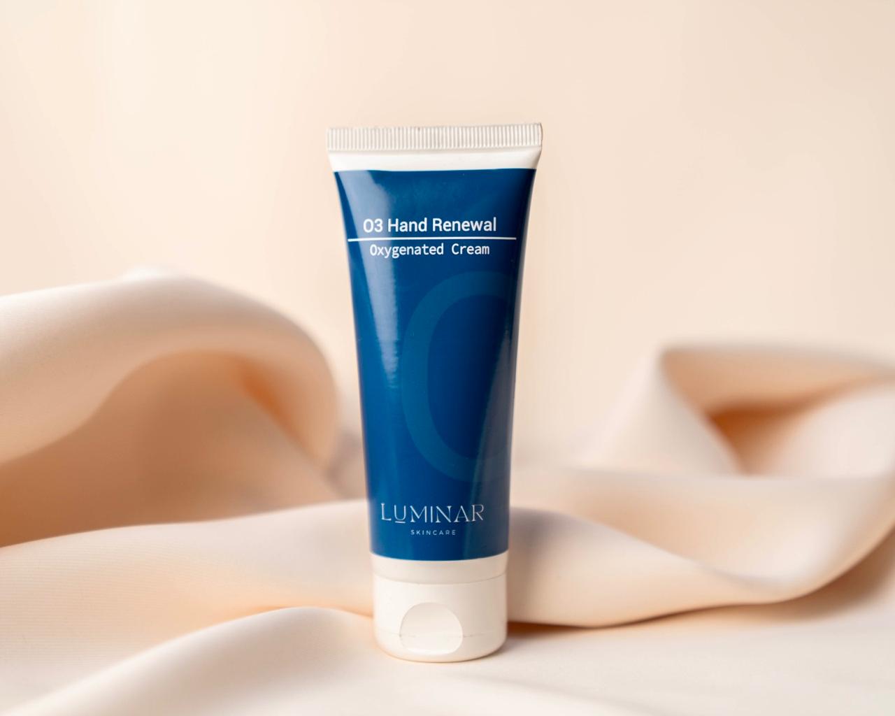 Luminar O3 Hand Renewal product elegantly displayed on neutral peach fabric, emphasizing hydration and care.