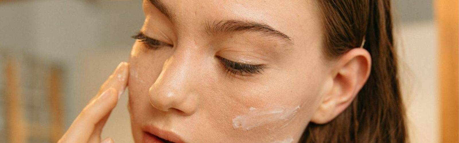 Woman gently applying facial cream as part of a skincare routine.